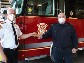 Chief Bryan VanGaver (left), with Sarnia Fire Rescue Services, hands Deputy Chief Ken Dwinnell his stripes on Nov. 2, on his first official day in the new post. Paul Morden/Postmedia Network