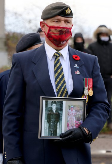 Roy Harten holds photographs of his cousin, Leonard Harten, who served in the merchant navy during the Second World War, and Sgt. John Nesom, a Sault Ste. Marie resident currently serving in Sudan during Remembrance Day service at cenotaph on Queen Street East in Sault Ste. Marie, Ont., on Wednesday, Nov. 11, 2020. (BRIAN KELLY/THE SAULT STAR/POSTMEDIA NETWORK)