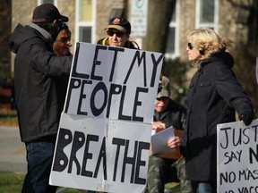 Jan Aikin, right, speaks with others demonstrating Saturday at Sarnia City Hall against pandemic restrictions.