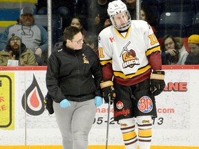 Rock trainer Lacey Rigg — one of two female head trainers in the NOJHL — assists Timmins blue-liner Evan Beaudry off the ice during a game at the McIntyre Arena during the 2019-20 campaign. The ongoing COVID-19 pandemic has made life a little more challenging for trainers across the league this season. FILE PHOTO/THE DAILY PRESS
