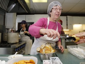 Volunteers Christine Osborn, centre, and Cheryl-Anne Giroux, left, serve lunch at Belleville's Salvation Army Community and Family Services building in 2018. Pandemic restrictions prevent the Army's winter Warm Room from opening, though takeout meals continue.