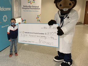 Brayden Vigneault presents a cheque to the Belleville General Hospital Foundations mascot, Dr. Max.