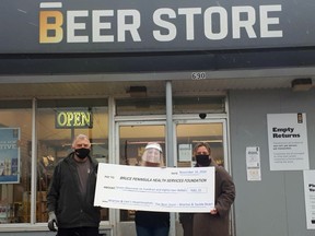 Wiarton and Sauble Beach Beer Store manager Trevor Couch, left, and Beer Store employee Shannon Gerencser, centre, present April Patry, executive director of the Bruce Peninsula Health Services Foundation, with a cheque for $7,682.20 in front of the Wiarton Beer store on Nov. 16 after a fundraising drive.