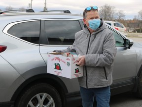 Volunteer Dave Kent takes a donation out of a vehicle during the drive-through food drive on Saturday morning at the Aud in Simcoe. (ASHLEY TAYLOR)