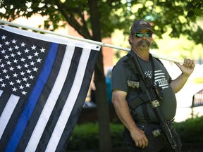 Josh Bradley holds a thin blue line flag during a Patriot Prayer and Peoples Rights Washington rally against the Washington state mask mandate Vancouver, Wash. Karen Ducey/Getty Images