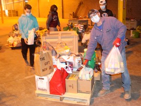 Jerome Quenneville shows these young guys how it's done as they sort through donations of food and toys local residents gave to The Gift CK, which held across Chatham-Kent on Nov. 21. Ellwood Shreve/Postmedia Network