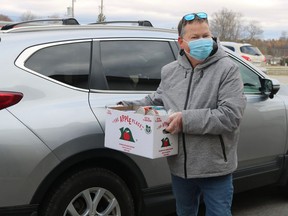 Volunteer Dave Kent takes a donation out of a vehicle during the drive-through food drive on Saturday morning at the Aud in Simcoe. Ashley Taylor/Postmedia Network