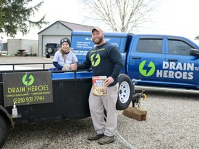 Chris Krauskopf, owner-operator of Drain Heroes in Delhi, and six-year-old daughter, Delilah, show where donations can be placed for the food and toy drive running this month in Delhi. (ASHLEY TAYLOR)