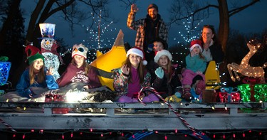 Justin Klassen (back centre), Julie Haywood (right), and family wave to passing vehicles from the MCR Advanced Collision Centre float during the annual Parade of Lights in Stratford on Sunday. Chris Montanini\Stratford Beacon Herald