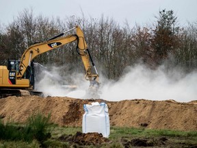 A bag of Calcium oxide is seen in the foreground as an excavator buries dead mink in ditches while members of Danish health authorities are assisted by members of the Danish Armed Forces in disposing of dead mink in a military area near Holstebro in Denmark on Monday, November, 9 2020. - Danish mink will be buried in mass graves on military land as the country's incinerators and rendering plants struggle to keep up, the Danish environmental and health authorities announced. Denmark will cull about 17 million mink after a mutated form of coronavirus that can spread to humans was found on mink farms. (Photo by Morten Stricker / Ritzau Scanpix / AFP) / Denmark OUT