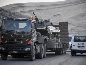Armenian army truck carries an APC (armoured personnel carrier) vehicle outside the disputed province's capital of Stepanakert on November 12, 2020, during the military conflict between Armenia and Azerbaijan over the breakaway region of Nagorno-Karabakh. (Photo by Alexander NEMENOV / AFP)