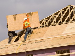 Workers build a roof on a new home build in West Brant.