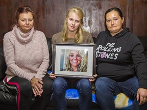 Debbie Burnside (left) and her daughters Caitlyn and Lindsay (right) hold a photo of Shannon (MacDougall) Burnside who was found dead in her Brantford home on March 11, 2020.