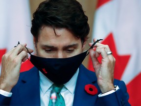 Canadian Prime Minister Justin Trudeau puts on a mask at a news conference held to discuss the country's coronavirus disease (COVID-19) response in Ottawa, Ontario, Canada. November 6, 2020. REUTERS/Patrick Doyle