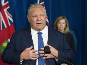 Ontario Premier Doug Ford answers questions during the daily briefing at Queen's Park in Toronto on Monday as Health Minister Christine Elliott listens.