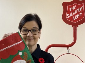 Owen Sound Salvation Army family services co-ordinator Alice Wannan stands in front of one of the organization's red kettles while holding one of the stockings that will be stuffed with treats and donated to a local senior. SUPPLIED