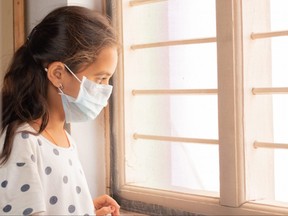 A girl looks out the window during home isolation in the COVID-19 pandemic.