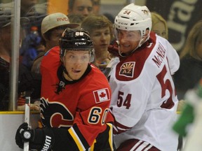 Patrick McNeill, in white, played for the Arizona Coyotes in a preseason game in September 2014. He's shown here tangling with Calgary Flames forward Markus Granlund. (File photo)