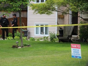 Sarnia police officers are shown in June outside a home in Bright's Grove, during an investigation into a shooting.