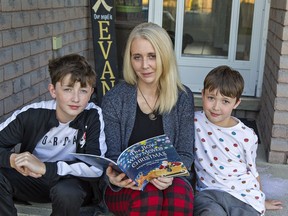 Nicole Wellwood and her two sons Logan, age 14 (left) and Tyson, 10 look over The Boy Who Moved Christmas, a book she helped write with Canadian children's author Eric Walters.