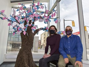 Gwen Howarth and Tye Patterson sit by a memorial tree on display at the Brantford Public Library.