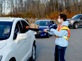 Nic Crowe shovels bags of candy to youngsters at the end of the Trunk or Treat route near O'Reilly's Your Independent Grocer in Prescott on Saturday afternoon. The drive-through event was also held near Brockville at Centennial Road Church, which originated the event 12 years ago. (TIM RUHNKE/The Recorder and Times)