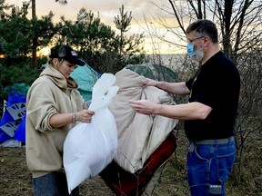 Caslyn, who lives in an encampment in the city's north end, recieves relief supplies from Mark Darrah, of Brockville Streetfriends. (RONALD ZAJAC/The Recorder and Times)