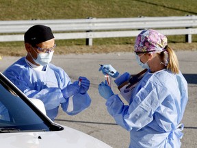 Dr. Ambrose Au, left, and public health nurse Joanne Desormeaux prepare a COVID-19 test outside the Brockville assessment centre on Wednesday afternoon. (RONALD ZAJAC/The Recorder and Times)