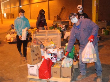 Jerome Quenneville shows these young guys how it's done as they sort through donations of food and toys local residents gave to The Gift CK, which held across Chatham-Kent on Saturday. Ellwood Shreve/Chatham Daily News/Postmedia Network