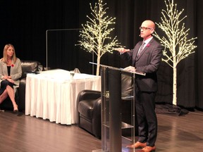 Mayor Jeff Genung speaks from a podium at the RancheHouse theatre November 5 while co-host, Cochranite and former TV news anchor Carla Minogue looks on. The pair were addressing Cochranites on the matter of traffic in a broadcast streamed over the internet.