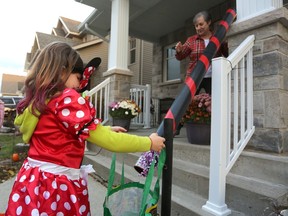 Lacey Dwyre collects candy via candy chute from Kathy Luffman in Kingston's west-end Woodhaven neighbourhood on Halloween evening on Saturday. (Meghan Balogh/The Whig-Standard)