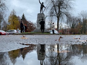 A group of people gather for an unofficial Remembrance Day ceremony at a military memorial in City Park in Kingston on Wednesday. (Elliot Ferguson/The Whig-Standard)