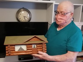 Trapper and outdoorsman Paul Peever of Kingston holds one of his beautiful handmade log cabin models, created by traditional log cabin building methods.