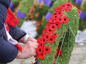 People attending the Remembrance Day ceremony at the Cross of Sacrifice in Kingston on Nov. 11, 2019, place their poppies on the People's wreath at the conclusion of the Remembrance Day ceremony. (Ian MacAlpine/The Whig-Standard)