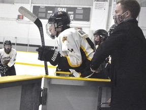 Mitchell U15 Tier 1 coach Owen Chaffe (right) opens the door for Kyle Mills (11) as he prepares to enter the play during WOAA action against BCH Nov. 11. The teams played two periods of 22-minute straight time hockey with no body contact, no penalties (penalty shots for infractions) and little or no rest. Mitchell won, 12-4. ANDY BADER/MITCHELL ADVOCATE