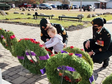 Sgt. Vanessa Jacobs looks on as her daughter Briella Johnson, 20 months, places a poppy on a wreath in front of the Petawawa cenotaph following the town's Remembrance Day ceremony at Branch 517 on Nov. 11. Also looking on is Master Warrant Officer Kelly Harding (right).