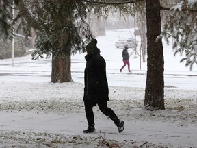 A woman goes for a walk during a snowy day in Sudbury, Ont. on Monday November 2, 2020.