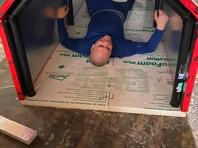 Todd Provincial lies inside a portable, insulated shelter he helped construct, demonstrating how much space and comfort it would provide for someone who lacks a proper roof over their head.