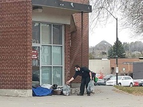 A passerby hands money to a homeless person camped out in front of the Sudbury Arena. City councillors are looking at ways to make life a bit easer for Sudbury's homeless and street-involved population.