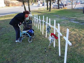A woman examines crosses placed near the Sudbury Theatre Centre at Paris Street and Brady Street in Sudbury, Ont.