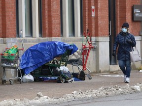 A person rests in front of the McEwen School of Architecture on Elgin Street in Sudbury, Ont. on Thursday November 26, 2020.