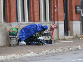 A person rests in front of the McEwen School of Architecture on Elgin Street in Sudbury, Ont. on Thursday November 26, 2020.