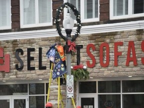 Woodstock city staff Wednesday changed the banners downtown for the holidays. While many of this year's festivities have been changed because of the COVID-19 pandemic, the city is still planning a virtual Tour of Lights and the light display downtown is now set up. (Kathleen Saylors/Sentinel-Review)