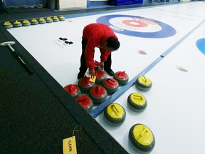 Orlo Mejia has the designated task of sanitizing his teams rocks at the conclusion of their senior men's curling game on Nov. 19. The yellow sticker shows next team on the ice the sanitization has been attended to.