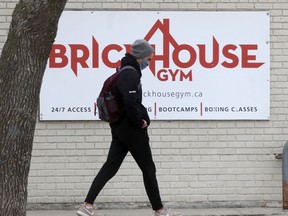 A person wearing a mask walks past a gym in mid-October.