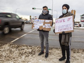 Jashan Brar (left) and Harsahay Singh  hold up protest signs at the intersection of 108 Street and 100 Ave Tuesday, Dec. 1, 2020, in solidarity with Indian farmers. The pair, along with two others on the east side of 108 Street, wanted to show that Indian farmers have support across the world.