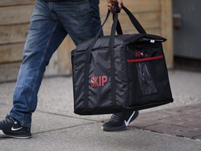 A Skip The Dishes delivery person carries a food carrier in Calgary on Friday, December 4, 2020. Azin Ghaffari/Postmedia