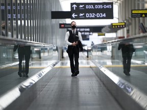 A man rides an escalator wearing mandatory masks at Toronto's Pearson International Airport in Toronto, Tuesday, June 23, 2020.