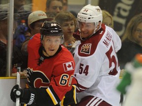 Patrick McNeill, in white, played for the Arizona Coyotes in a preseason game in September 2014. He's shown here tangling with Calgary Flames forward Markus Granlund. File photo/Postmedia