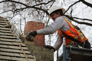 Brennen Guest removes bricks from the chimney of the Canatara Park cabin. The nearly 200-year-old cabin is being moved to the Lambton Heritage Museum in Lambton Shores.
